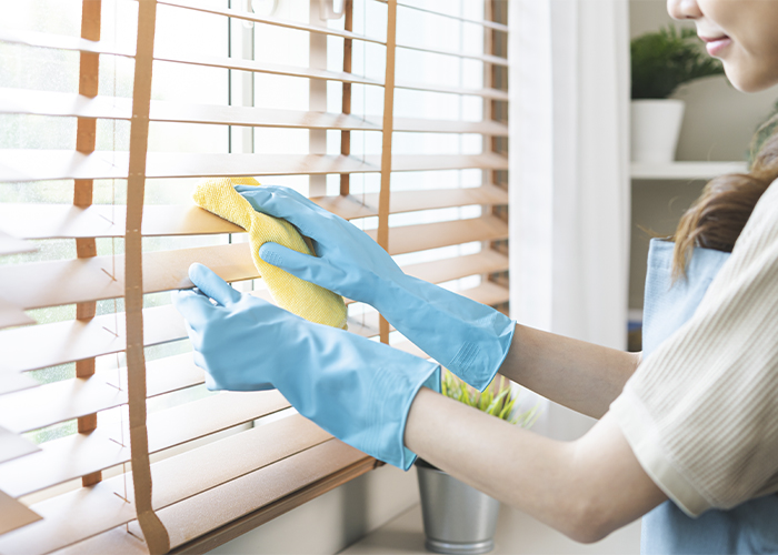 A professional cleaner carefully wipes blinds as part of residential and commercial cleaning services in Phoenix.